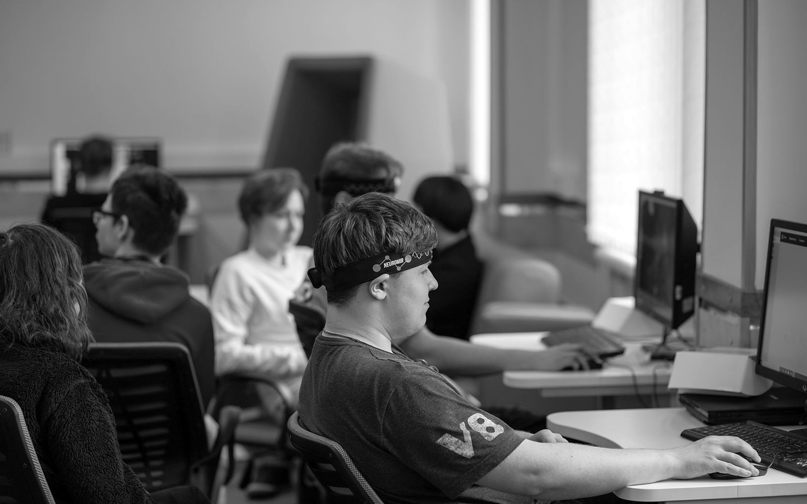 Estudiantes concentrados, cada uno en su computadora, en un aula de informática.